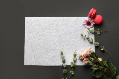 Güzel çiçekler, macarons ve boş kağıt koyu arka plan üzerinde