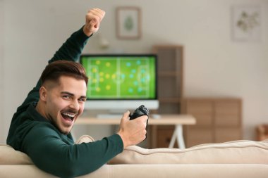 Happy young man after winning video game at home