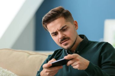 Genç adam evde Smartphone oyun oynama