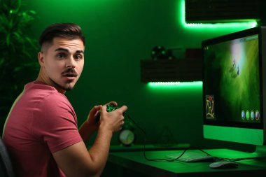 Şaşırmış genç adam kulüpte bilgisayar oyunu oynamak