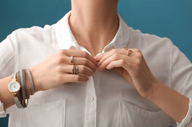 Beautiful young woman with stylish bijouterie on color background, closeup
