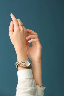 Hands of beautiful young woman with stylish bijouterie on color background