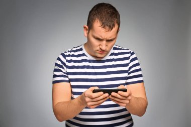 Gri arka plan üzerinde smartphone oyun kaybettikten sonra kızgın genç adam