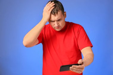 Smartphone oyun renk arka plan üzerinde kaybettikten sonra kızgın genç adam
