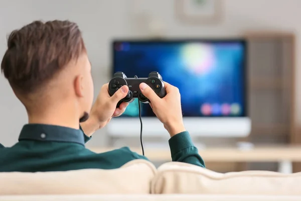 Young man playing video game at home