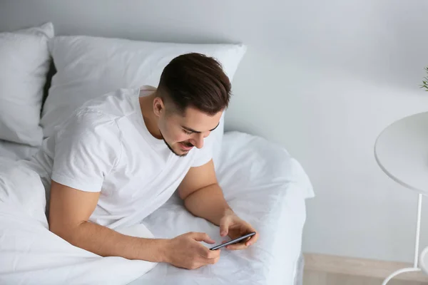 Νεαρός Άνδρας Που Παίζει Παιχνίδι Στο Smartphone Στο Κρεβάτι — Φωτογραφία Αρχείου