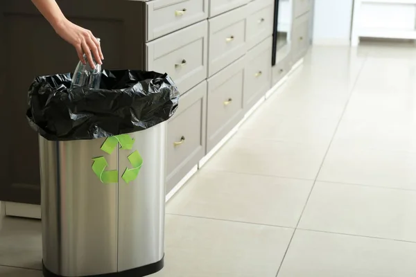 若い女性が自宅のゴミ箱に空のペットボトルを投げます リサイクルの概念 — ストック写真