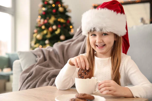 Ładna Dziewczynka Santa Hat Gorąca Czekolada Picia Jedzenia Ciasteczka Domu — Zdjęcie stockowe