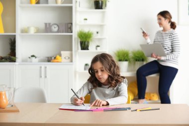 Sevimli küçük kız annesi evde çalışma sırasında çizim