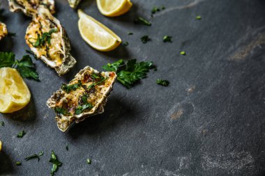 İstiridye limon ve koyu arka plan üzerinde otlar pişmiş lezzetli