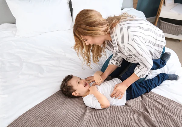 Sevimli küçük oğluyla evde yatakta oynayan genç anne