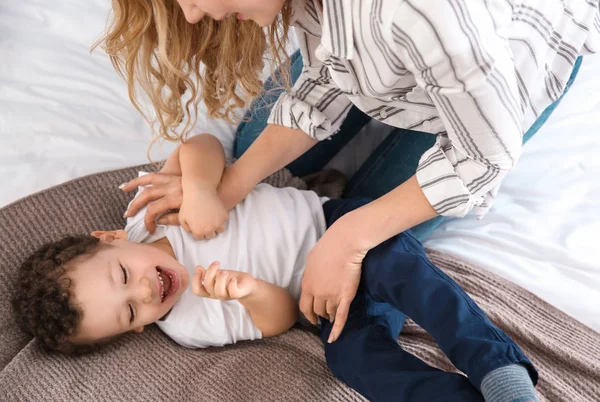 Sevimli küçük oğluyla evde yatakta oynayan genç anne