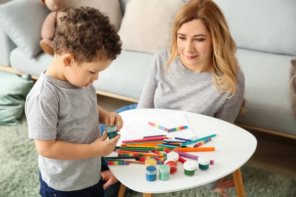 Cute little boy with mother drawing at home