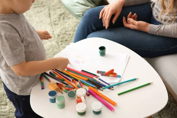 Cute little boy with mother drawing at home