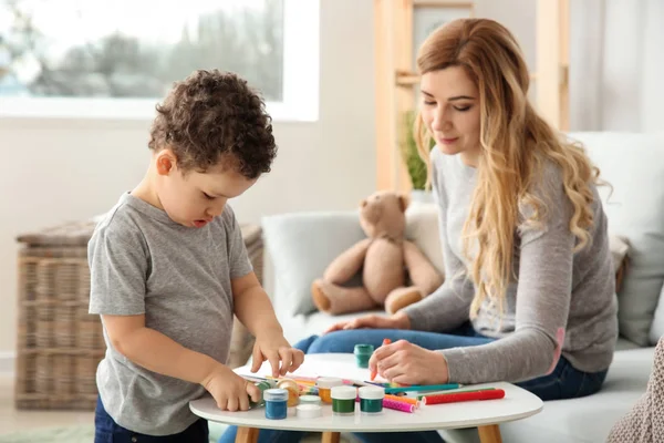Cute little boy with mother drawing at home