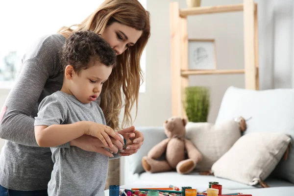Cute little boy with mother drawing at home