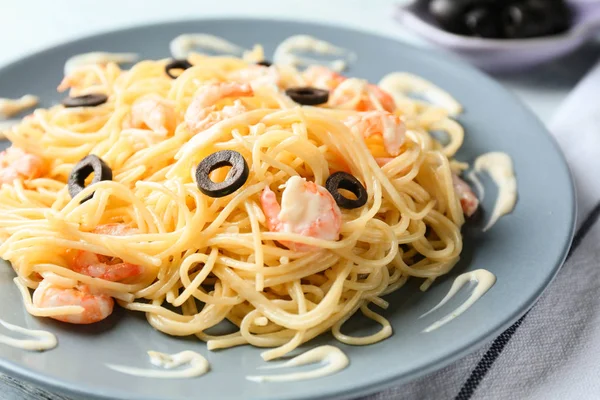 Tasty pasta with shrimps and olives on plate, closeup