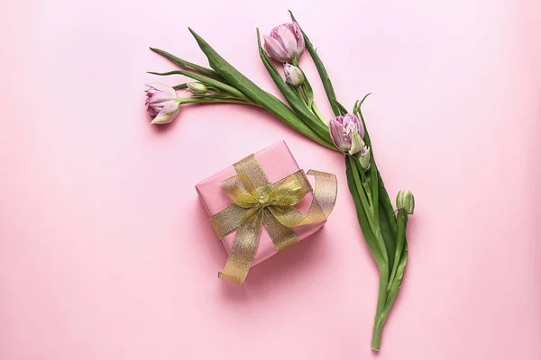Festive gift box and flowers on color background