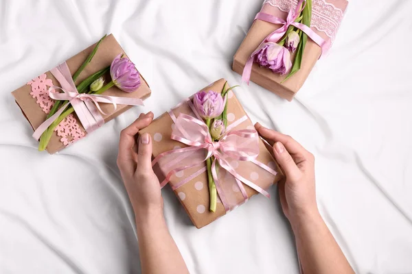 Frauenhände Mit Handgemachten Geschenkschachteln Und Blumen Auf Hellem Hintergrund — Stockfoto