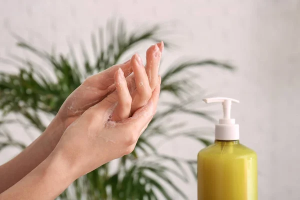 Woman washing hands with liquid soap at home