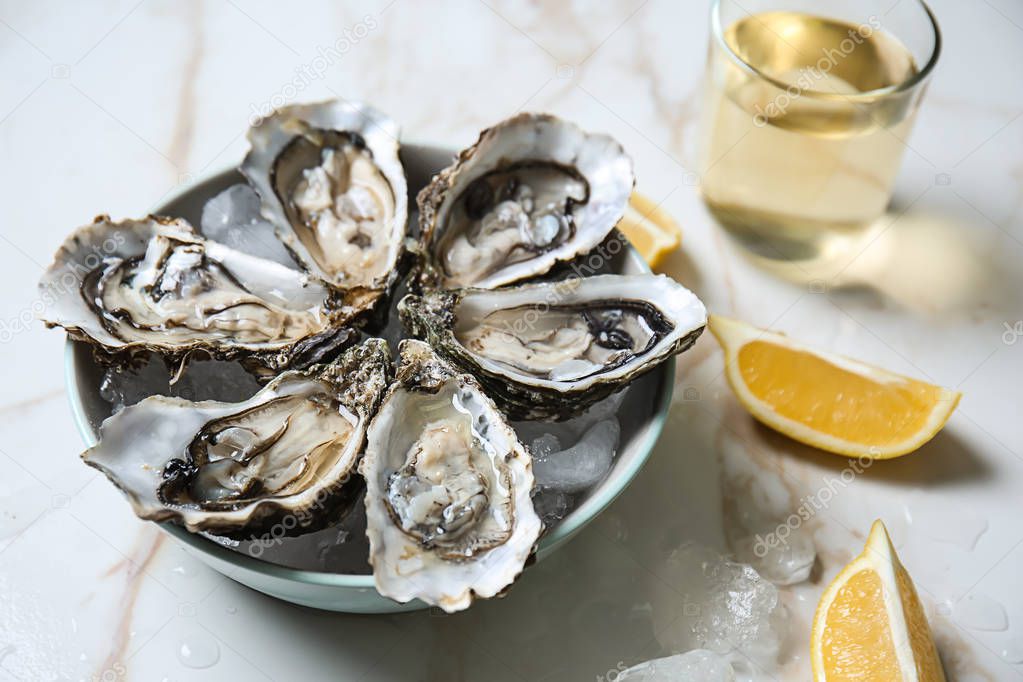 Plate with tasty cold oysters on light table