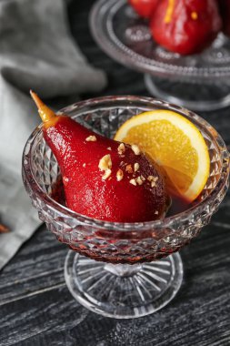 Ahşap masa üzerinde kırmızı şarap lezzetli haşlanmış armut ile cam kase