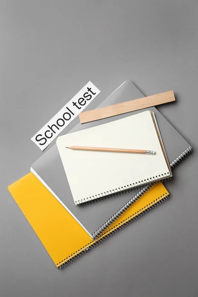 Stationery and paper with text SCHOOL TEST on grey background