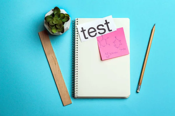 School stationery and paper with word TEST on color background