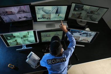 Güvenlik görevlisi gözetleme odasındaki modern güvenlik kameralarını izliyor.