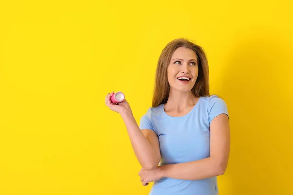 Beautiful young woman with deodorant on color background