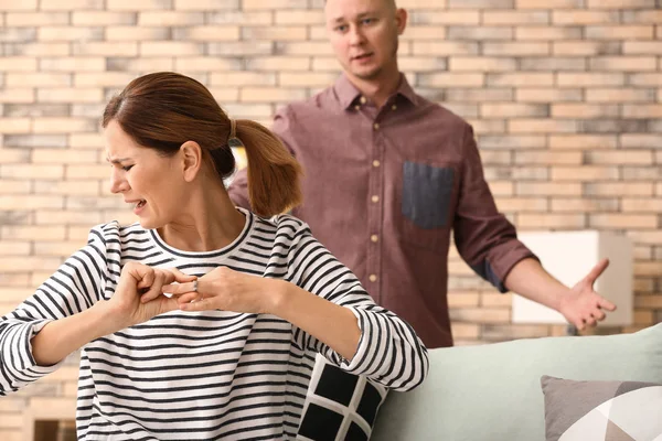 Unhappy woman trying to slip wedding ring off finger at home. Concept of divorce