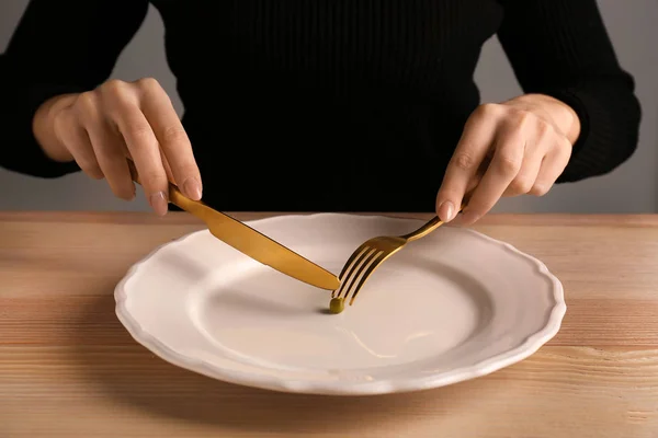 Young woman cutting small peas at table, closeup. Diet concept