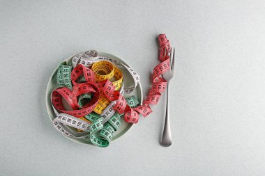 Hafif arka planda ölçüm bantları ile çatal ve plaka. Diyet kavramı