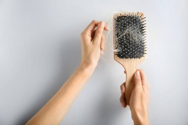 Fırça ile hafif arka plan üzerinde saç düşmüş tutan eller