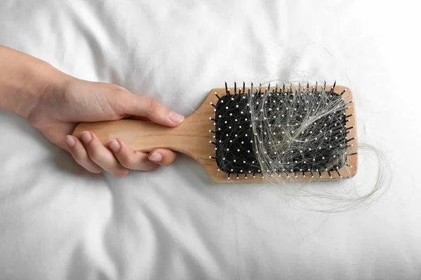 Kadın Fırça Ile Yumuşak Yastık Üzerinde Saç Düşmüş Tutarak — Stok fotoğraf