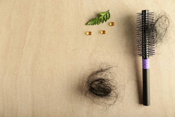 Brush with fallen down hair and fish oil pills on wooden background