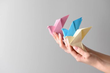 Origami kuşlar ışık arka plan üzerinde eller