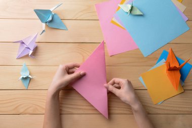 Genç kadın üzerinde ahşap masa origami yapma