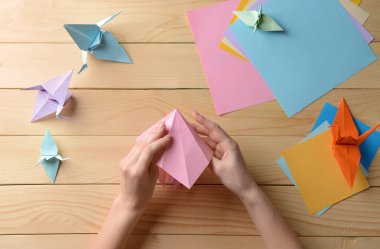 Genç kadın üzerinde ahşap masa origami yapma