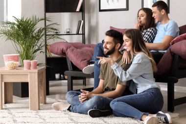 Arkadaşlar evde televizyon izliyor.