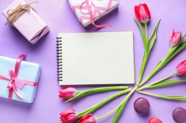 Boş defter, hediye kutuları ve renk arka plan üzerine güzel çiçekler ile kompozisyon