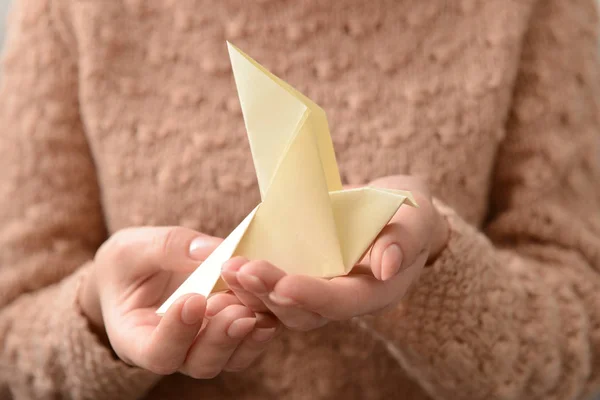 Young woman holding origami bird, closeup
