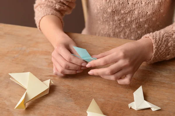 Young woman with origami bird at table, closeup