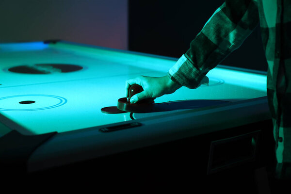 Женщина играет в современный воздушный хоккей
