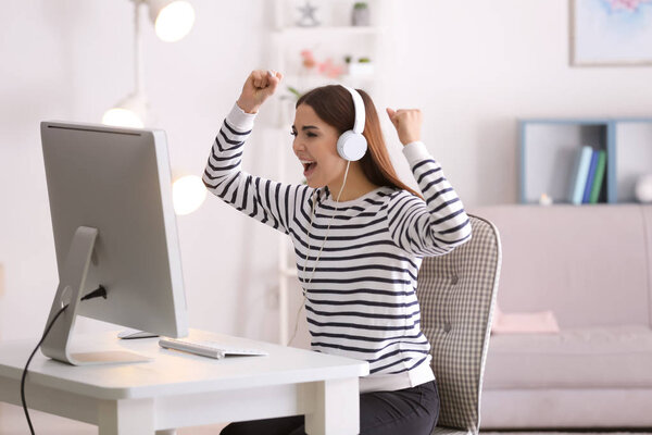 Emotional young woman playing computer game at home