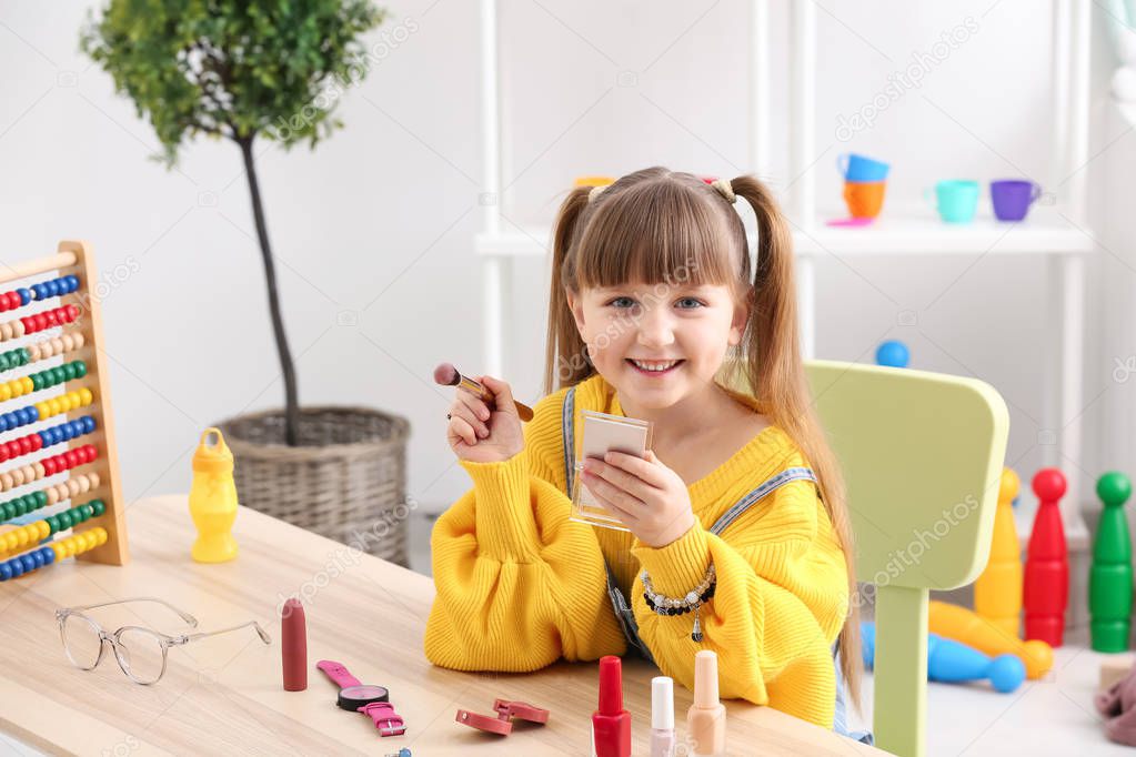 Cute little fashionista with cosmetics at home