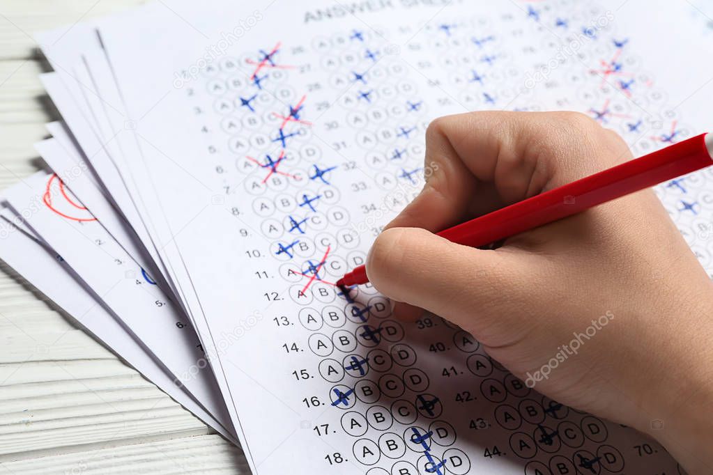 Teacher checking answer sheet after exam, closeup