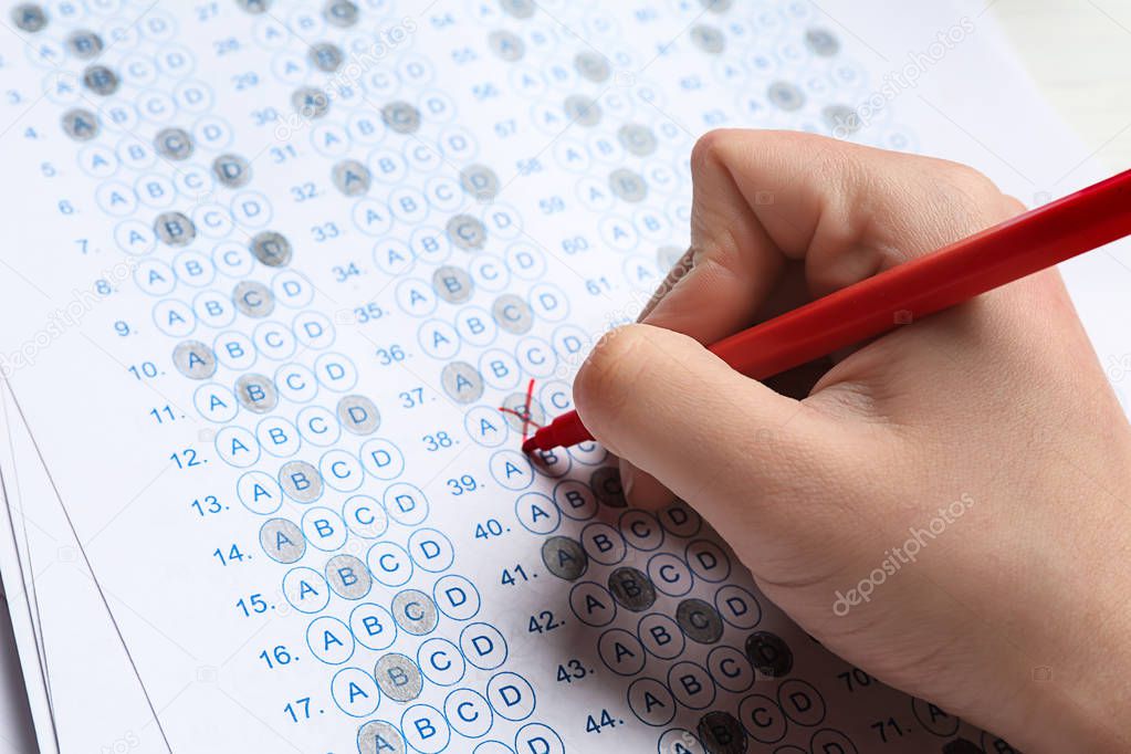 Teacher checking answer sheet after exam, closeup