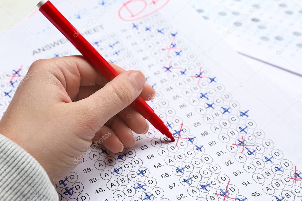 Teacher checking answer sheet after exam, closeup