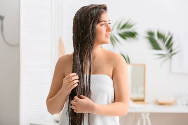 Banyoda güzel uzun saçlı krem uygulayarak genç kadın